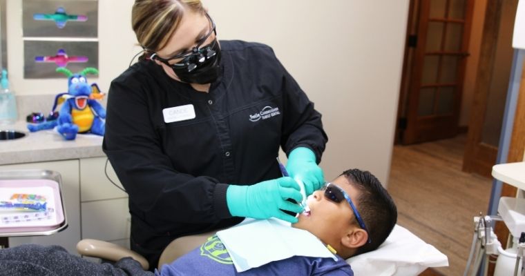 An hygienist with a young male patient getting preventive dental care