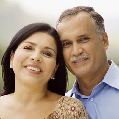 An older couple smiling due to dental implants