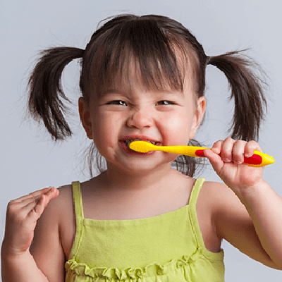 A young girl brushing her teeth to prevent cavities