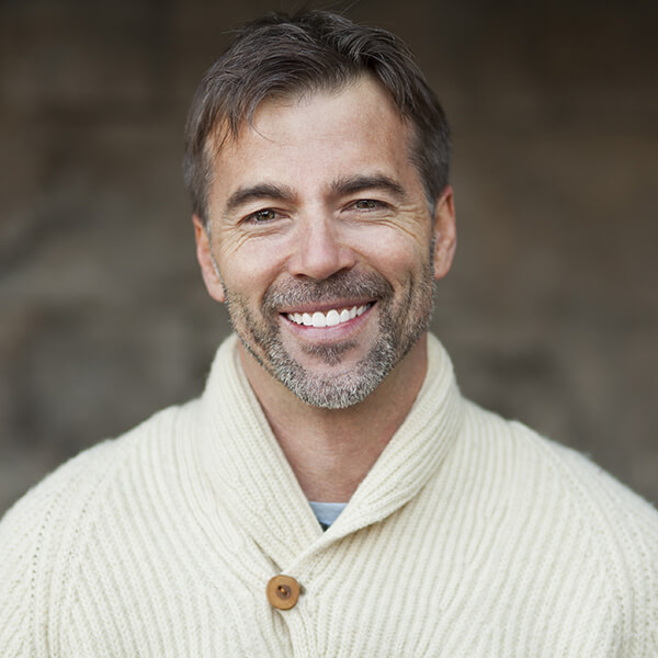 Man wearing a warm sweater and smiling after a root canal